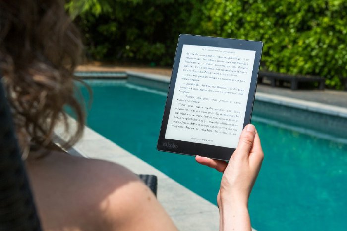 Woman reading on a kindle by a pool